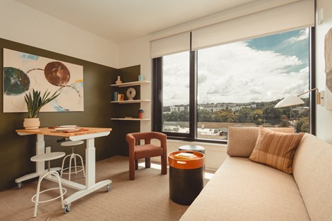 A living room with a couch, a table, a chair, and a painting on the wall.