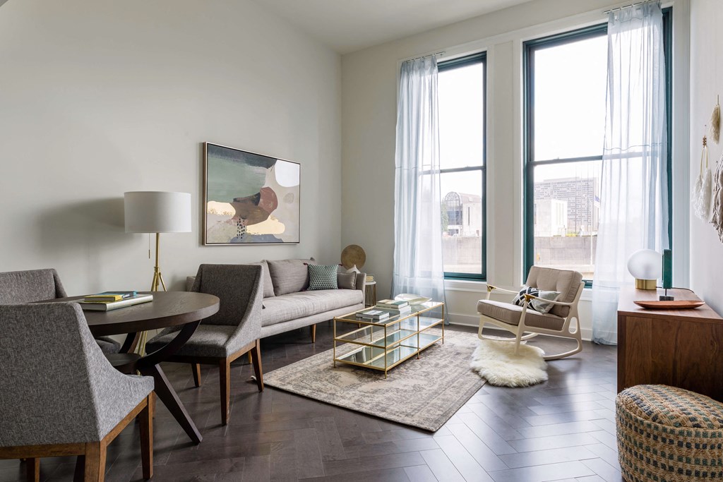 A living room with a grey couch, a coffee table, and a painting on the wall at The Pennsylvanian Apartments, Pittsburgh, PA, 15222