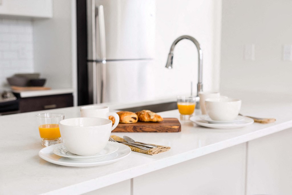 A breakfast setting with a glass of orange juice, a cup of coffee, and a plate of croissants at The Pennsylvanian Apartments, Pittsburgh, 15222