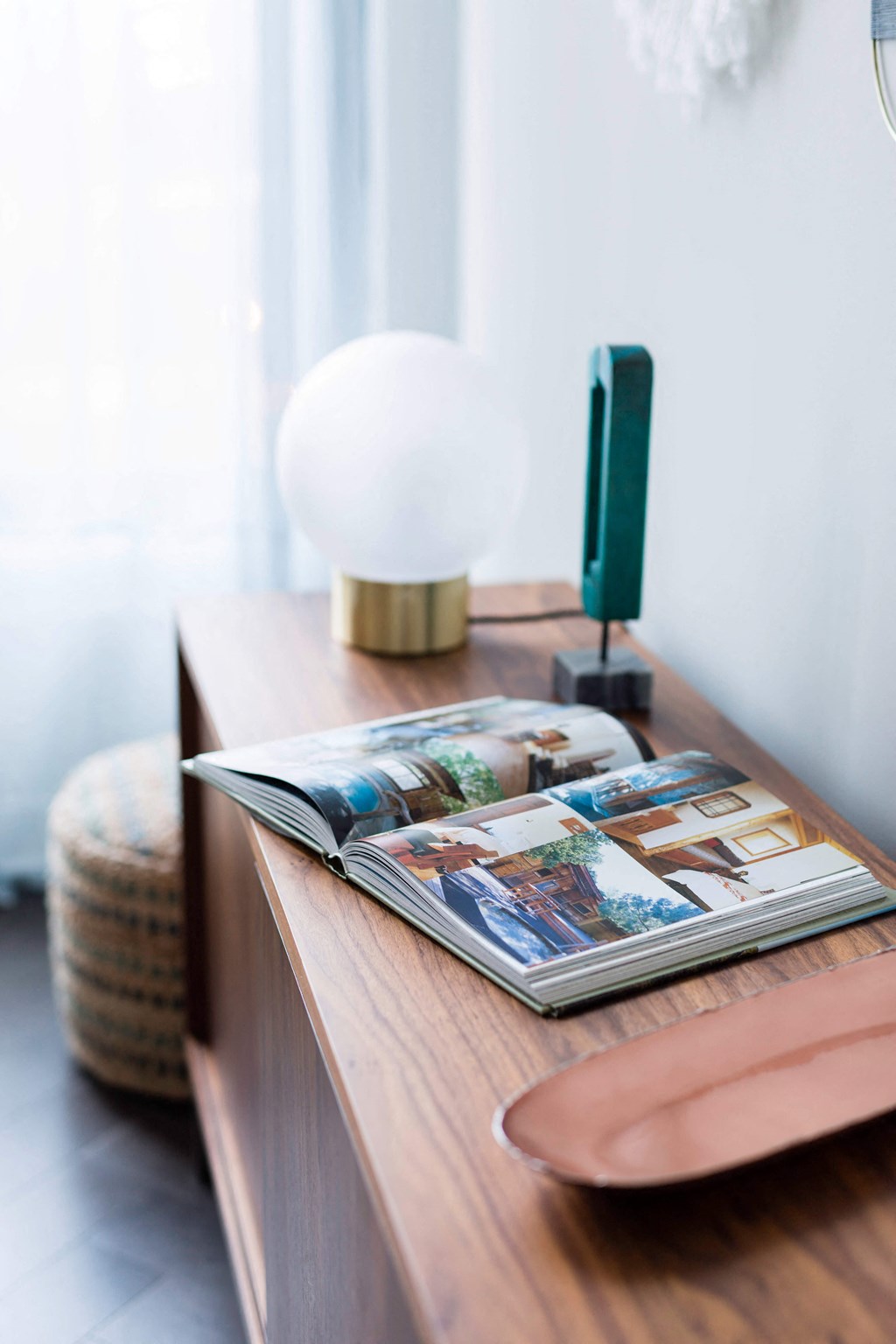 A magazine is open on a wooden table with a lamp and a green object beside it at The Pennsylvanian Apartments, Pennsylvania