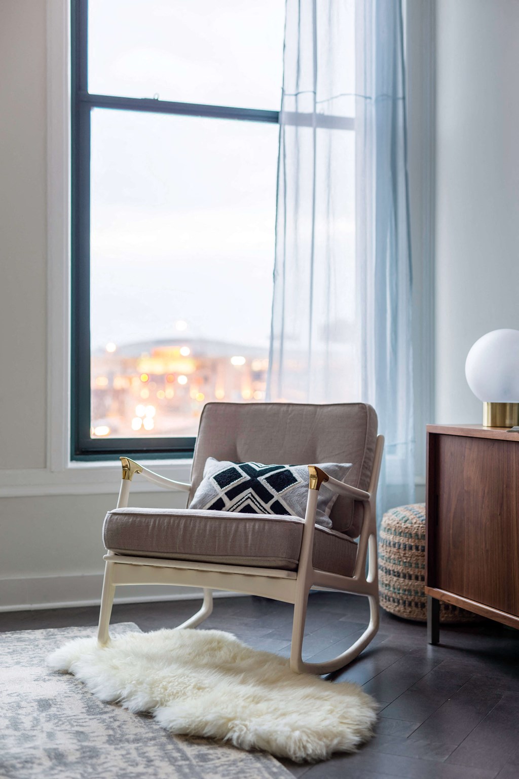 A chair with a cushion and a pillow is in front of a window at The Pennsylvanian Apartments, Pittsburgh
