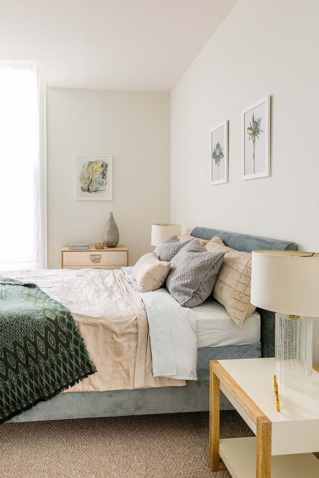 A bedroom with a bed, nightstand, lamp, and two framed pictures on the wall at The Pennsylvanian Apartments, Pittsburgh, PA