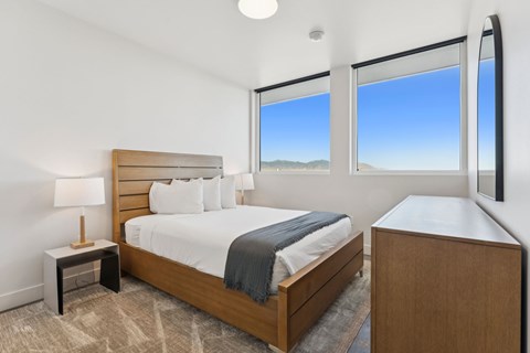 A bedroom with a large bed and a nightstand with a lamp.