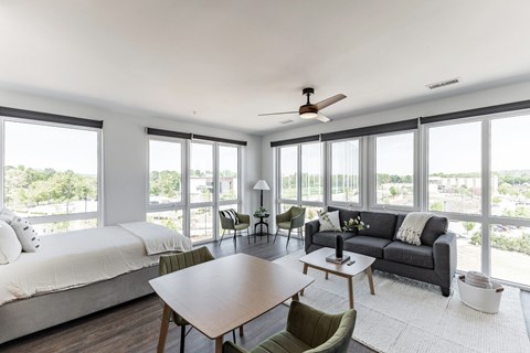 A modern bedroom with a large bed and a spacious living area with a couch and chairs.