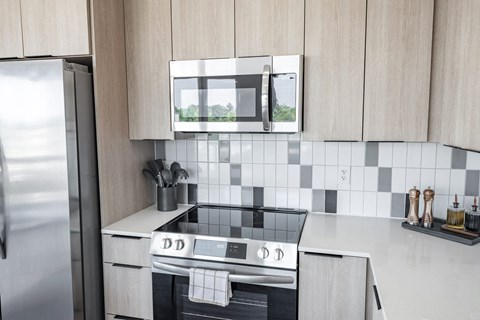A modern kitchen with a stove top oven and a microwave above it.