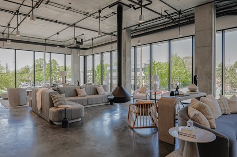 A modern living room with a large grey sofa and a glass wall.