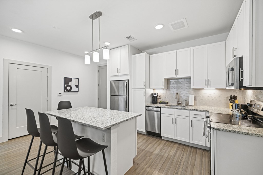 A modern kitchen with a dining table and chairs.at Placemakr Downtown Austin, Texas