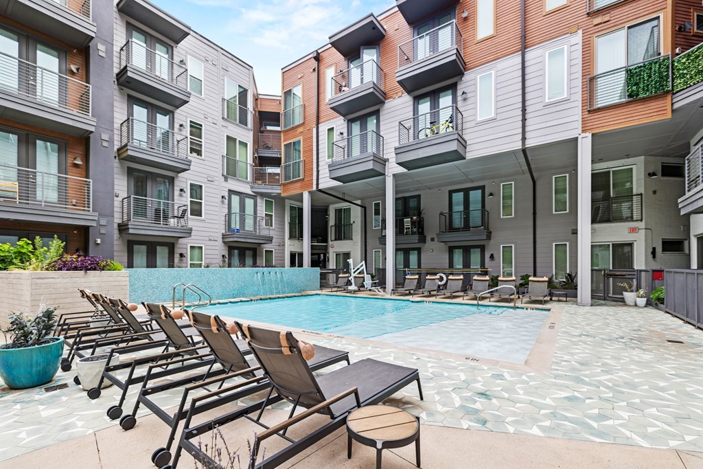 A swimming pool surrounded by lounge chairs and buildings.at Placemakr Downtown Austin, Austin Texas