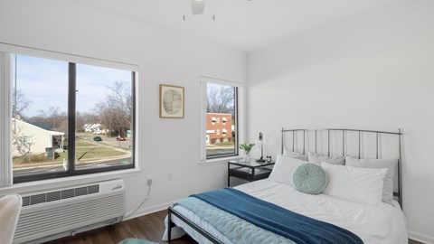 A bedroom with a bed, nightstand, and window.