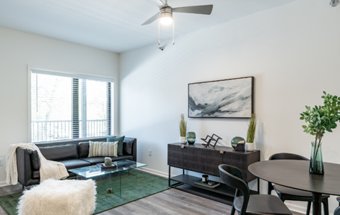 A living room with a couch, chairs, and a painting on the wall.