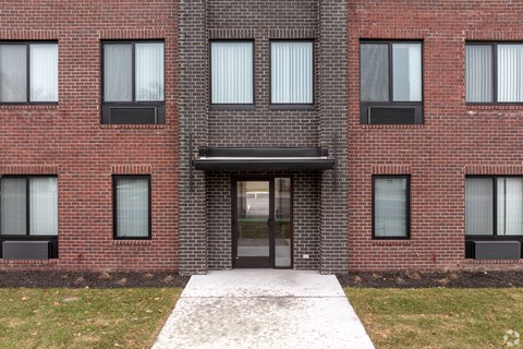 A red brick building with a black awning and a glass door.