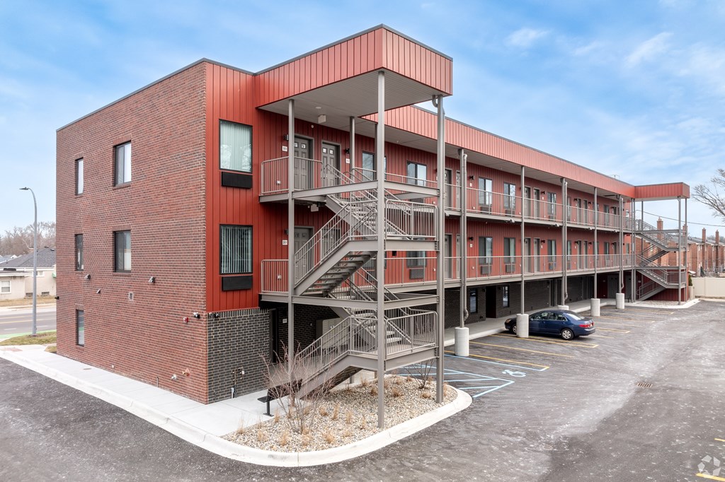 A red brick building with a parking lot in front.
