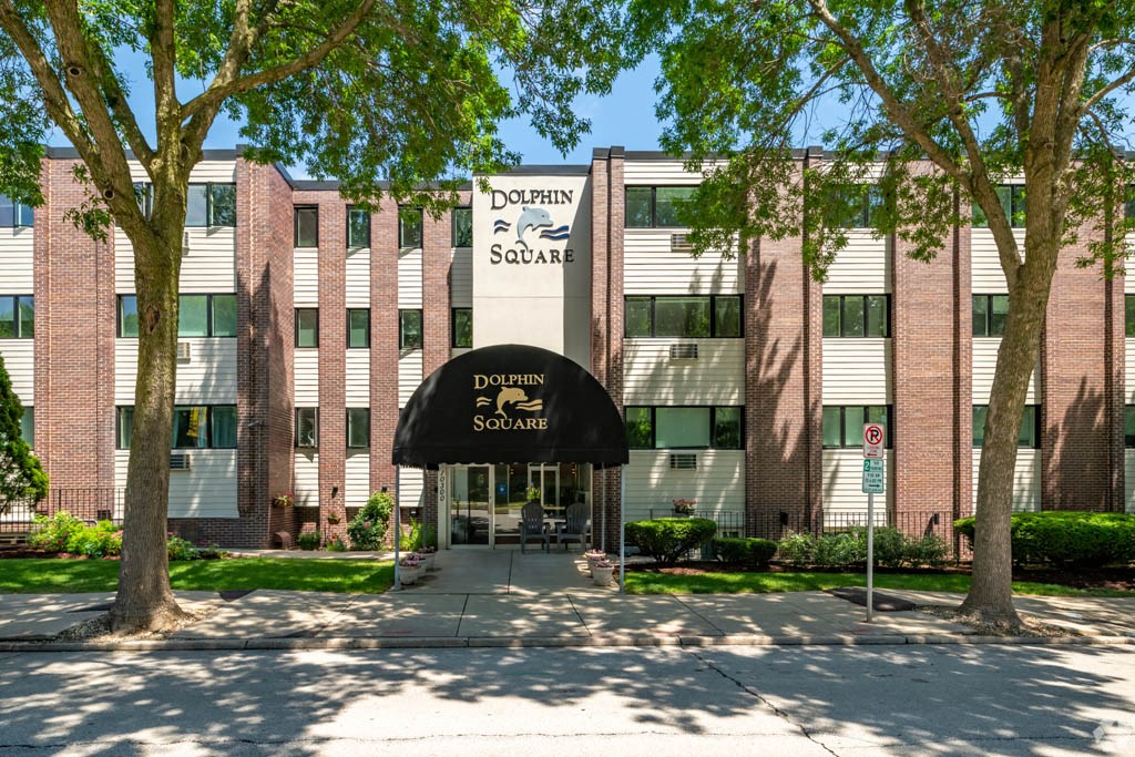 a brick building with a black awning and trees in front of it