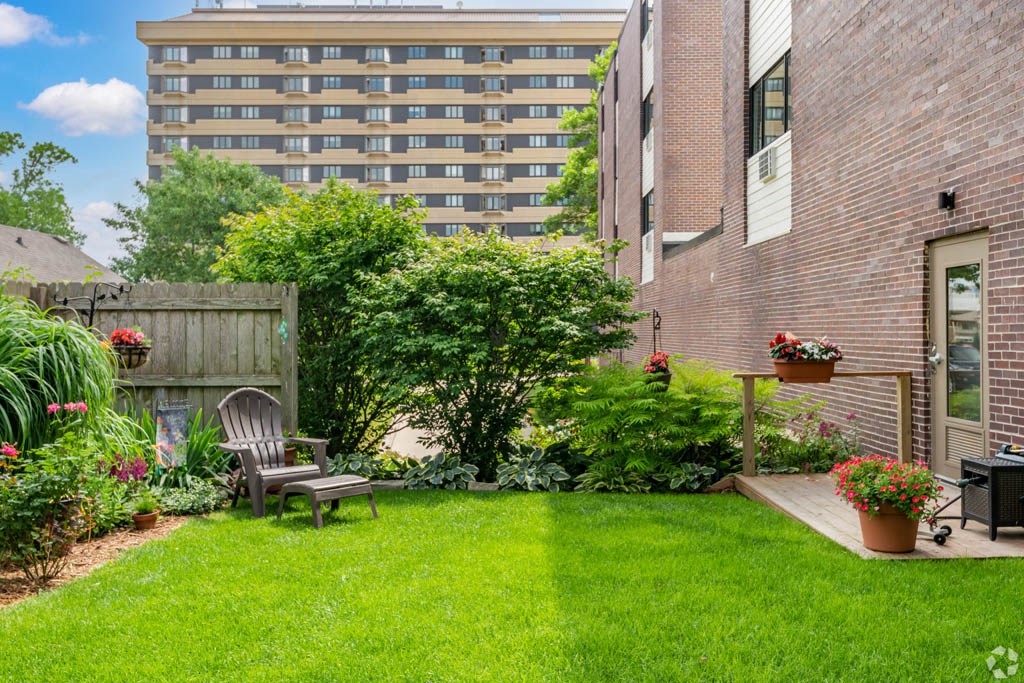 a backyard with green grass and a chair in front of a building
