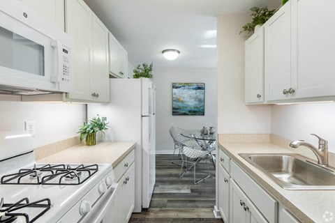 a kitchen with white cabinets and appliances and a sink