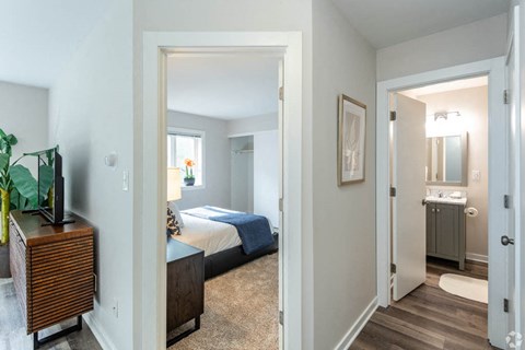 a bedroom and a bathroom with a bed and a mirror