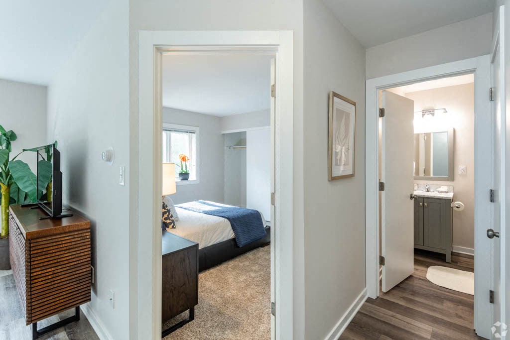 a bedroom and a bathroom with a bed and a mirror