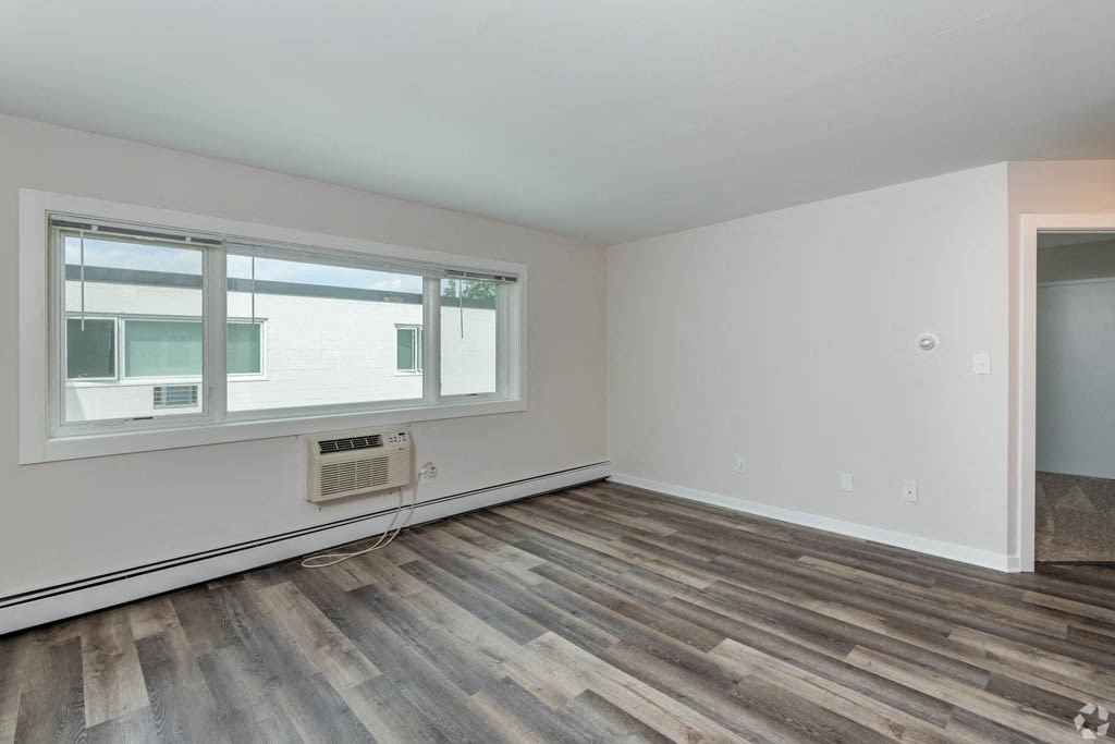 the living room of a home with wood flooring and a window