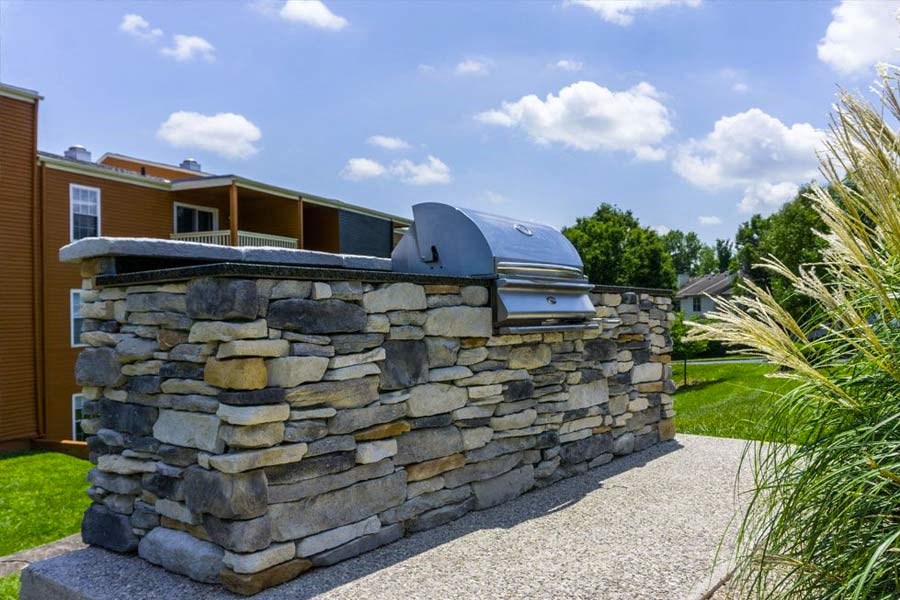 a stone bar with a grill on it in front of a house