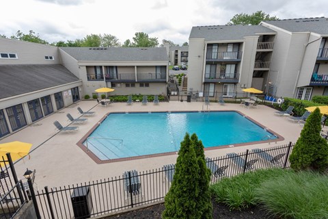 A pool surrounded by a black fence and a building in the background.