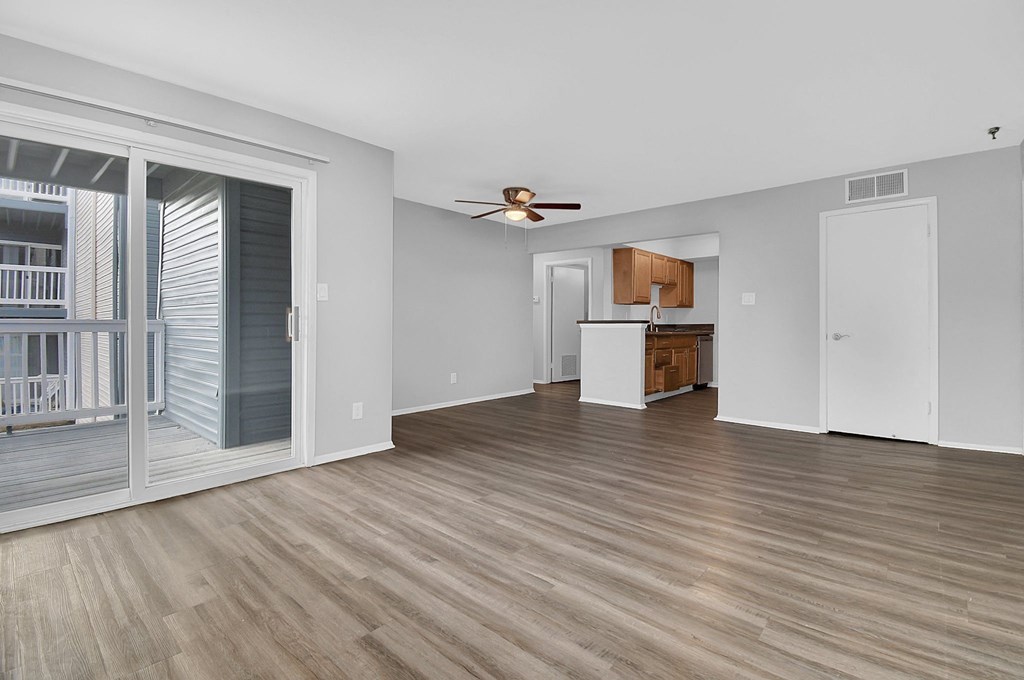 a living room with a ceiling fan and sliding glass door to a balcony
