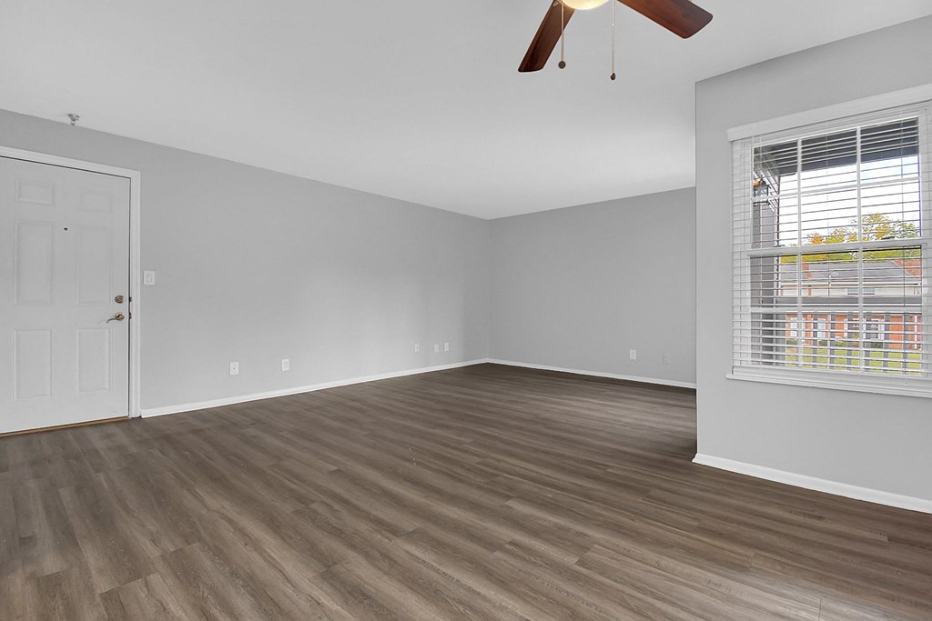 an empty living room with wood flooring and a window