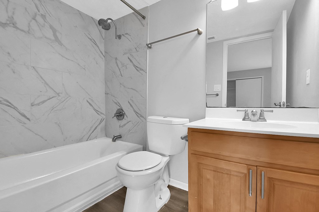 a bathroom with a toilet sink and tub and a mirror