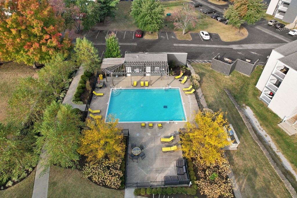 an aerial view of a swimming pool in a yard with yellow chairs