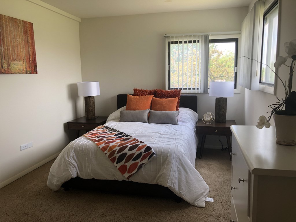 a bedroom with a bed and two lamps and a window