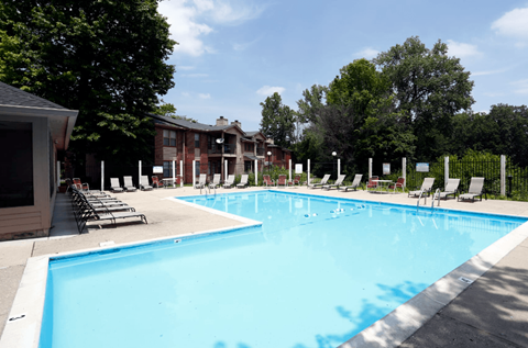 A large swimming pool surrounded by chairs and trees.