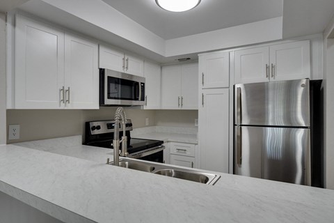 A kitchen with white cabinets and a stainless steel refrigerator.