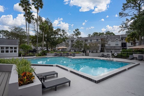 A swimming pool surrounded by benches and trees.