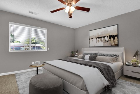 A bedroom with a large bed, a ceiling fan, and a window with blinds.