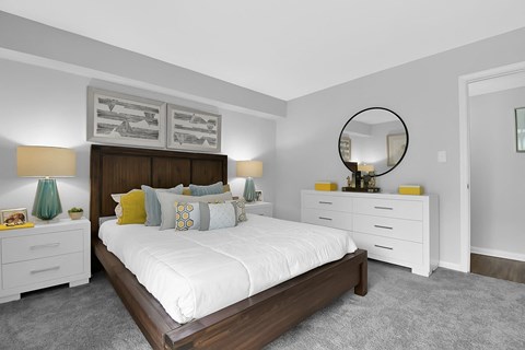 A bedroom with a large bed, nightstands, and a mirror.
