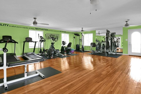 A gym with a variety of equipment including treadmills, weights, and exercise machines.