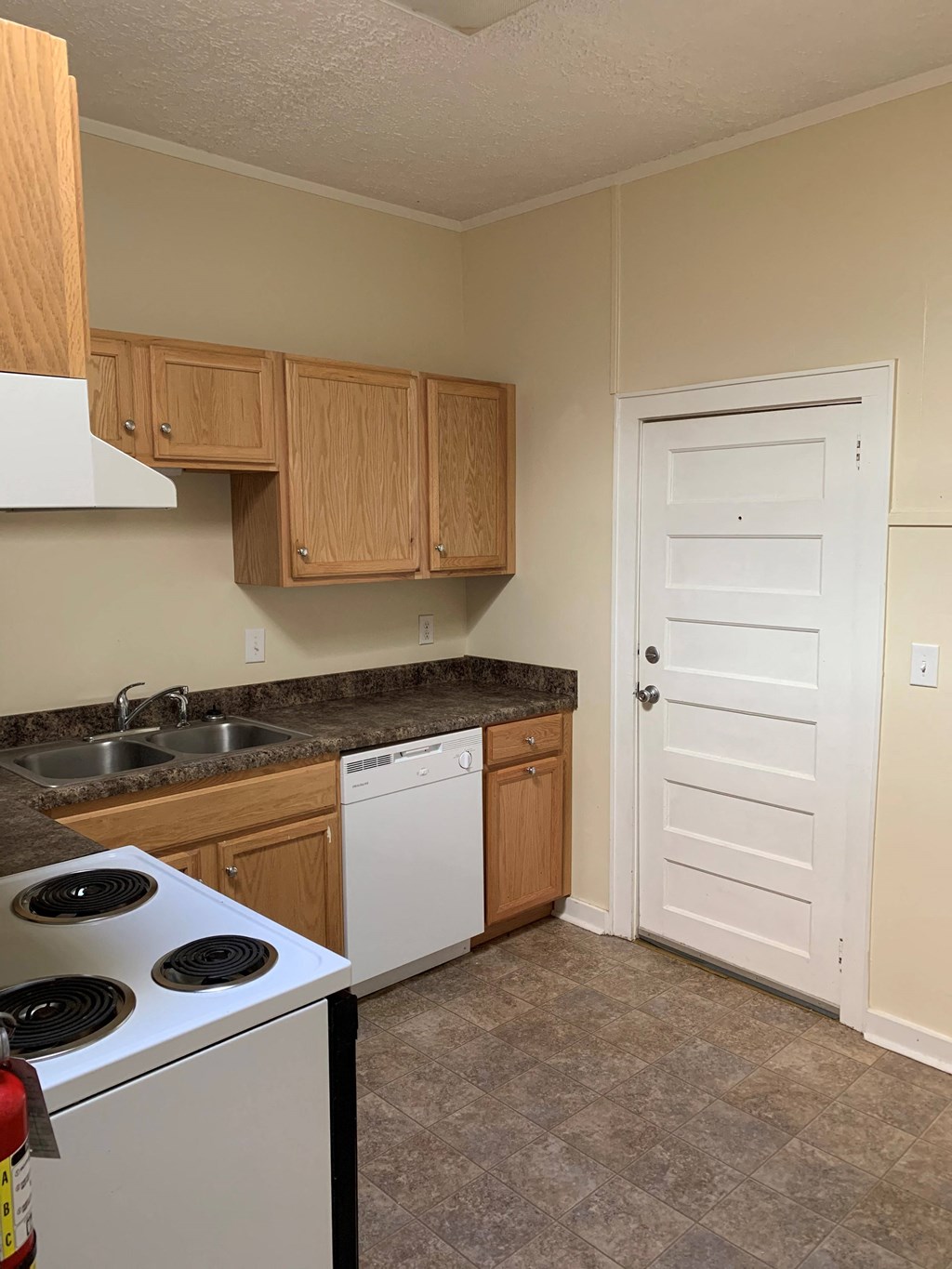 a kitchen with a stove and sink and a white door