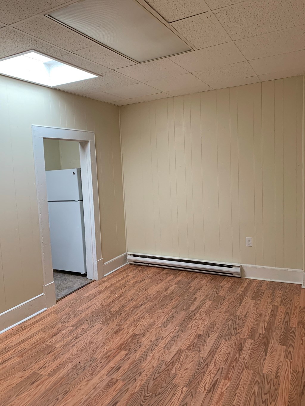 a living room with a refrigerator and a wooden floor