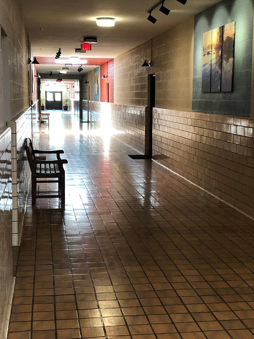 a hallway in a building with a chair and tiled floors