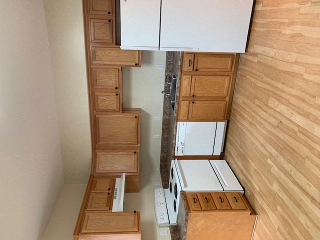 a kitchen with cabinets and a stove and a staircase