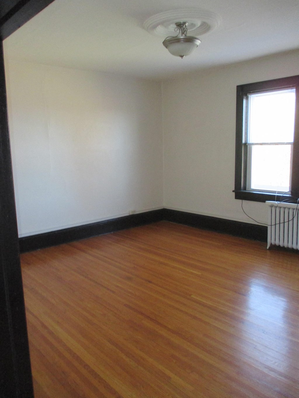 an empty living room with wooden floors and a window
