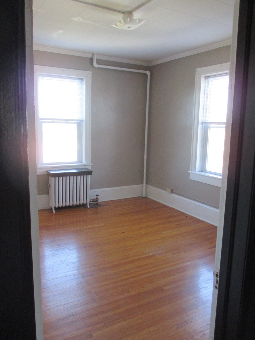 an empty room with a wood floor and two windows