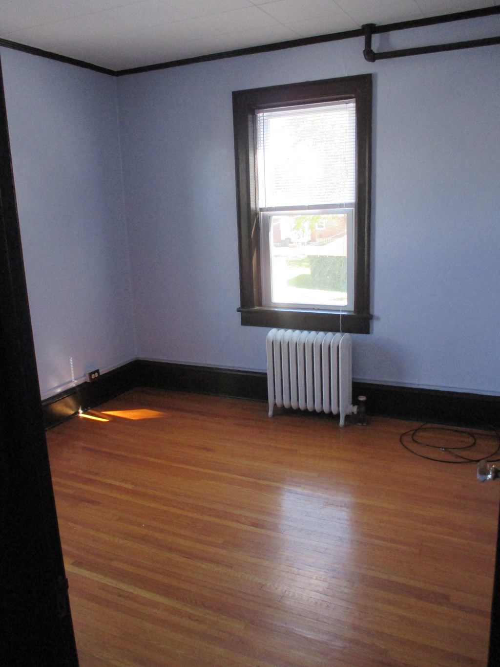 an empty room with a window and wooden floors