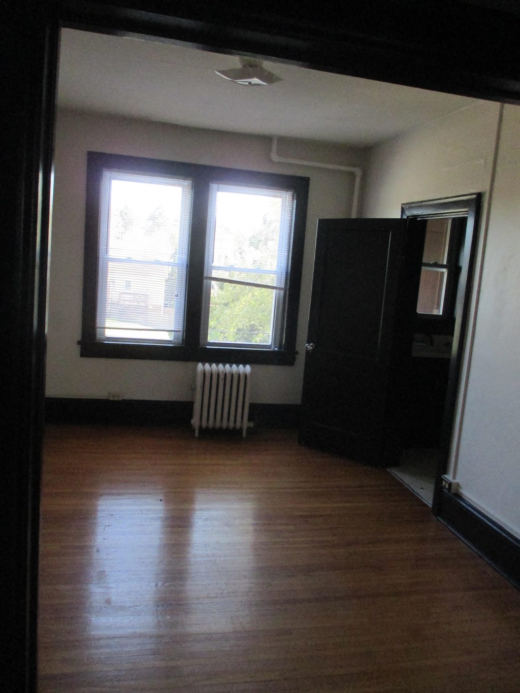 a living room with a wooden floor and two windows