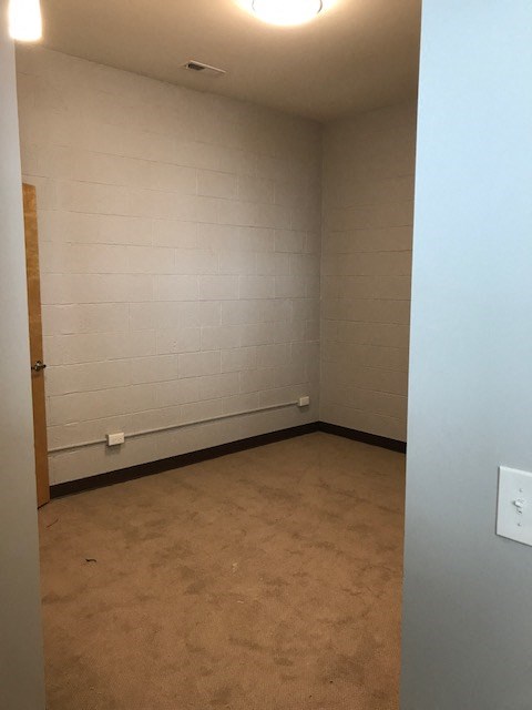 an empty room with a white wall and a brown floor