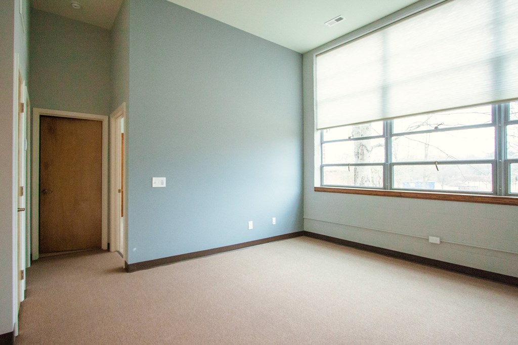 an empty room with a large window and a door