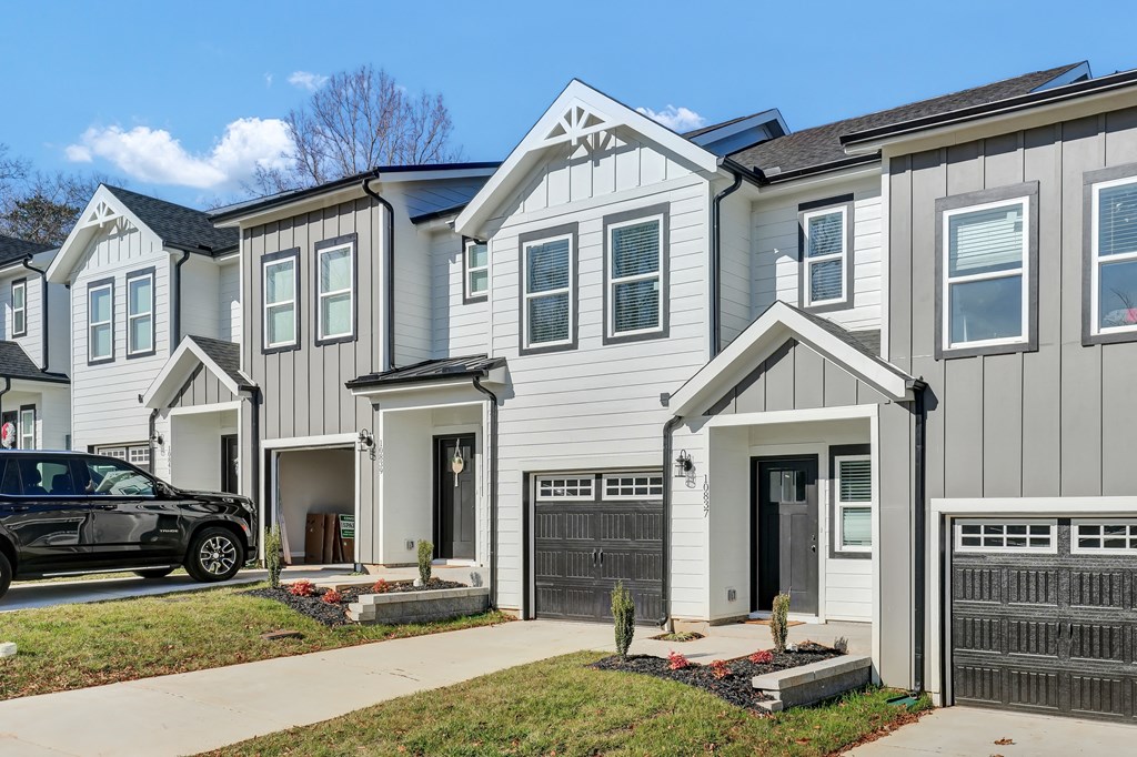a row of white homes with a black car parked in front