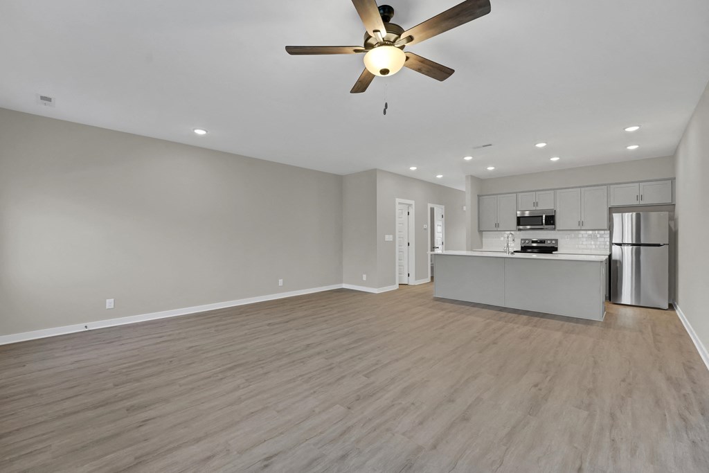 an empty living room and kitchen with a ceiling fan