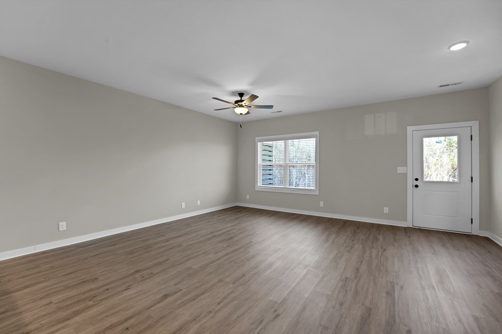 an empty living room with wood floors and a ceiling fan