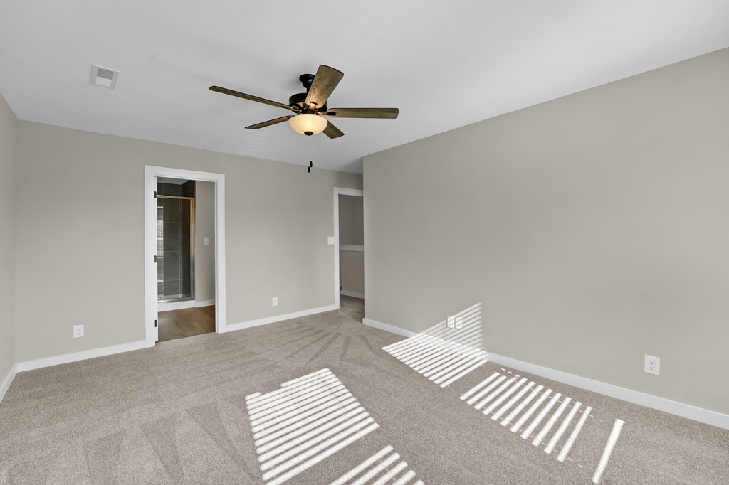 an empty living room with a ceiling fan and shadows on the floor