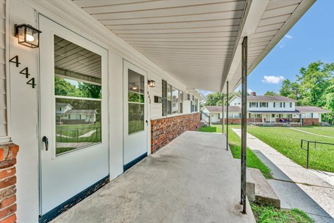A white building with a brick wall and a number 444 on the door.